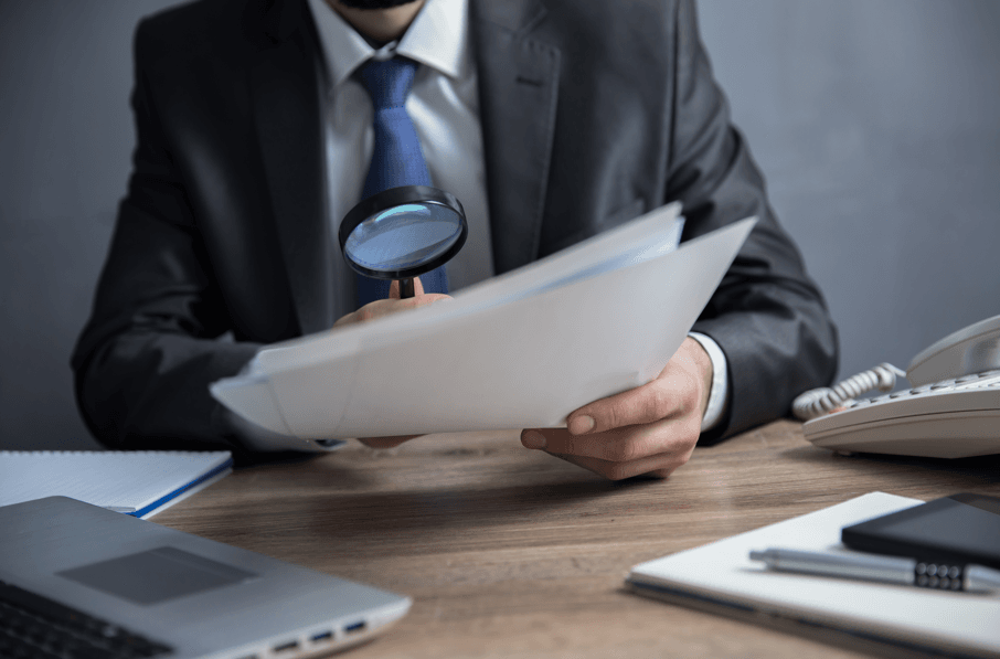Advogado especialista em PAD: homem analisando documento com lupa.