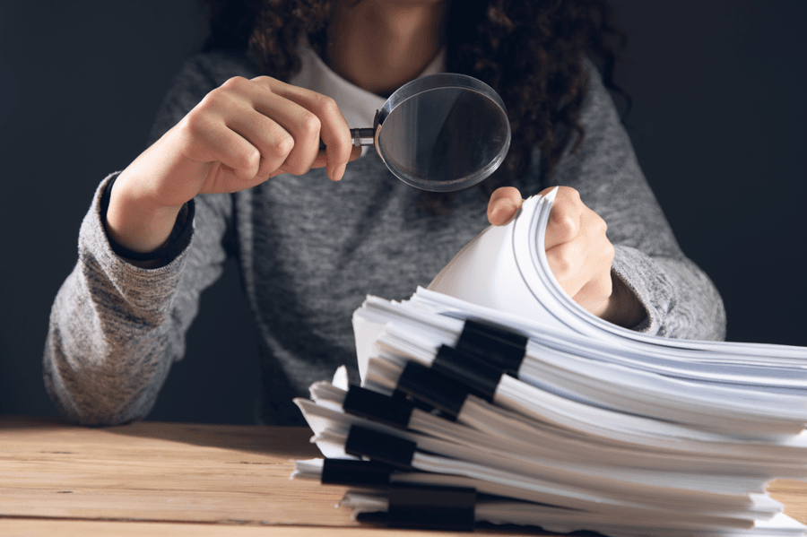Mulher segurando documentos e lupa, fazendo referência ao direito ao contraditório na sindicância administrativa.