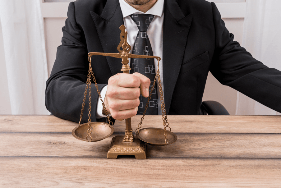 Homem segurança balança da justiça, fazendo referência aos critérios e limites no relatório final no processo administrativo disciplinar.