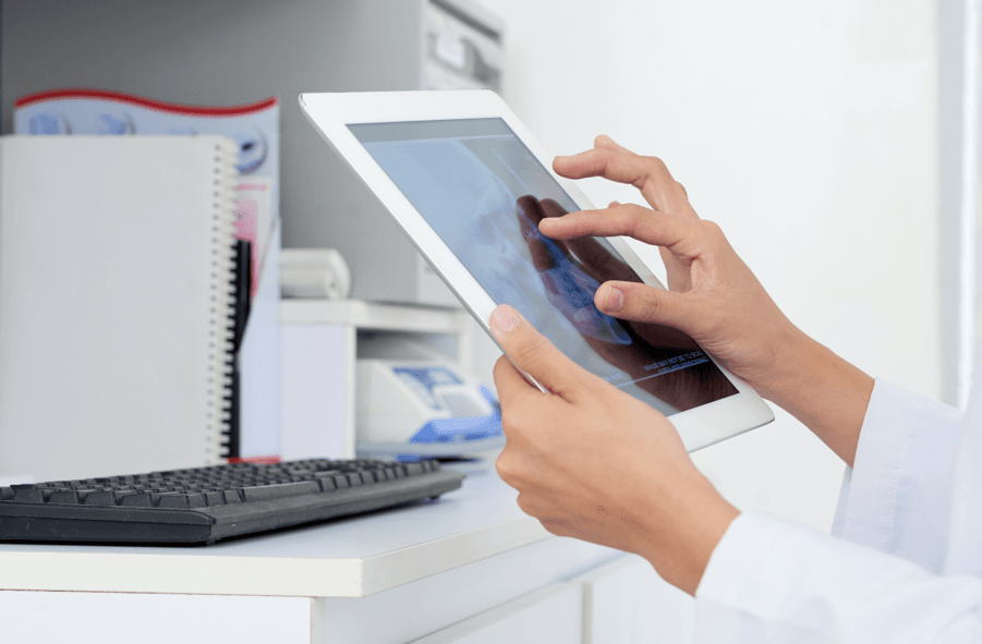 Tratamento médico adequado: mãos da médica olhando exame de raio-x no tablet.