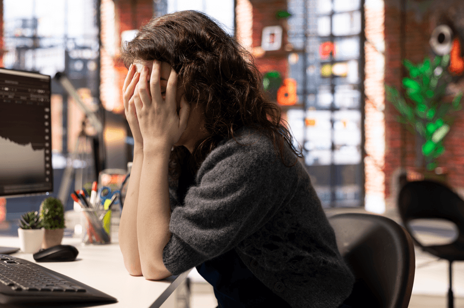 Como provar que a depressão do servidor público foi causada pelo trabalho: mulher com a mão sobre o rosto no trabalho.